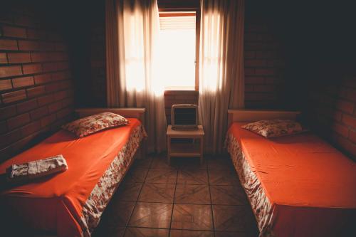 two beds in a room with a window and a tv at Pousada Scursel in Ibirama
