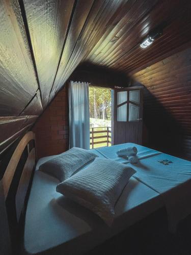 a bedroom with a bed with blue sheets and a window at Pousada Scursel in Ibirama
