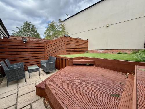 a wooden deck with two chairs and a table at Private 2BR house, Cheltenham Centre & Parking in Cheltenham