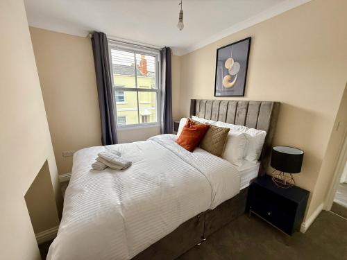 a bedroom with a bed with white sheets and a window at Private 2BR house, Cheltenham Centre & Parking in Cheltenham