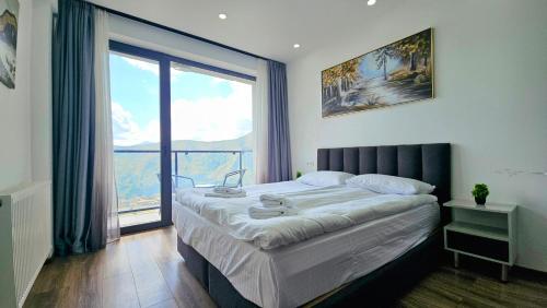 a bedroom with a large bed and a large window at New Gudauri Twins Mountain view in Gudauri
