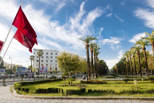 a red flag in a park with palm trees at Barceló Fès Medina in Fez