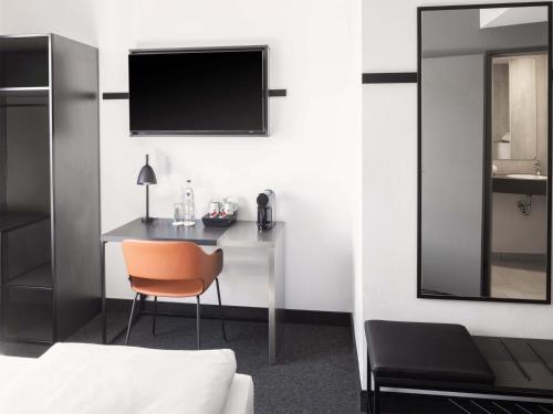 a bedroom with a desk with a television and a chair at B&B Hotel Kiel-City in Kiel