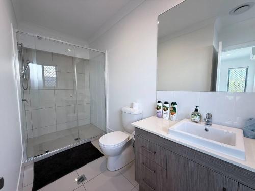 a bathroom with a toilet and a shower and a sink at Sparkling New Home - Suburban Charm Awaits! in Marsden