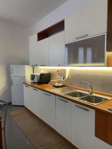 a kitchen with white cabinets and a sink and a refrigerator at Roero House in Asti