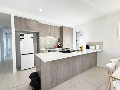 a kitchen with a white refrigerator and a counter at Sparkling New Home - Suburban Charm Awaits! in Marsden