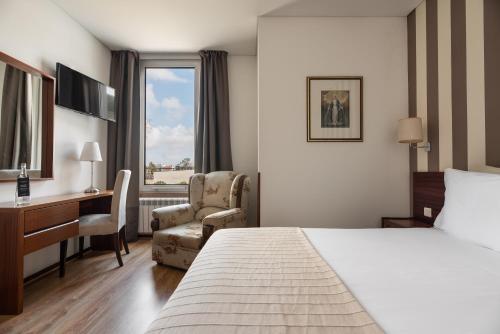 a hotel room with a bed and a desk and a chair at Crisol Tres Pastorinhos in Fátima