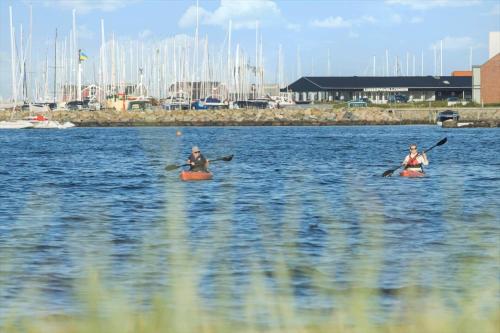 two people kayaking on a body of water with boats at 40128-Juelsminde-Strandengen-41 in Juelsminde