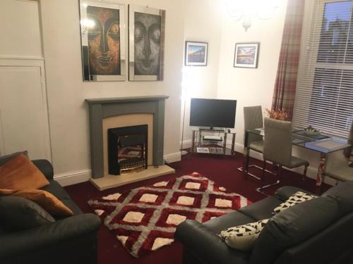 a living room with a couch and a fireplace at Woodlands Holiday Apartments in Lytham St Annes