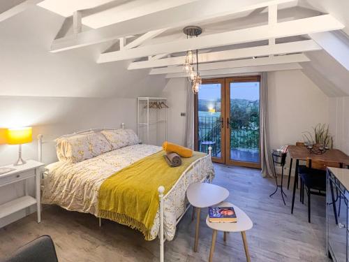 a white bedroom with a bed and a table at Wysteria, North Lodge in Rusper