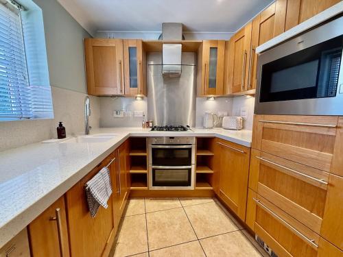 a kitchen with wooden cabinets and a stove top oven at Spacious 5BR, Cheltenham Town centre, inc parking in Cheltenham