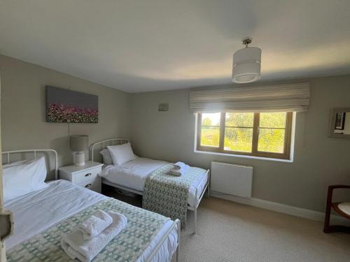 a bedroom with two beds and a window at Nestled in the heart of a stunning Suffolk Village in Chediston