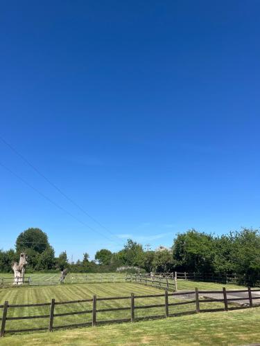 a field with a fence and a statue in the distance at Nestled in the heart of a stunning Suffolk Village in Chediston