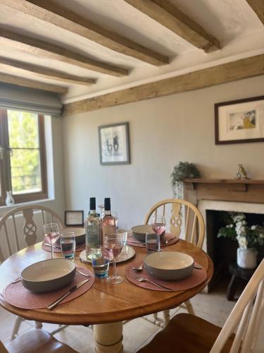 a wooden table with plates and wine glasses on it at Nestled in the heart of a stunning Suffolk Village in Chediston