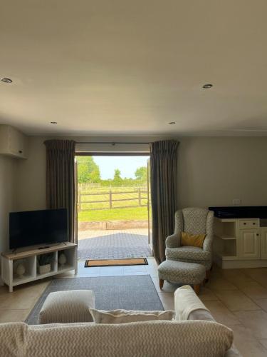 a living room with a couch and chairs and a television at Nestled in the heart of a stunning Suffolk Village in Chediston