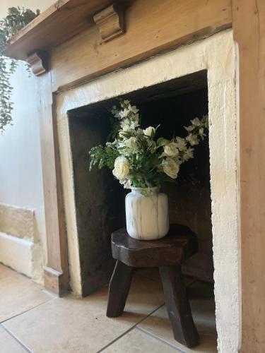 a vase of flowers sitting on a table in a fireplace at Nestled in the heart of a stunning Suffolk Village in Chediston