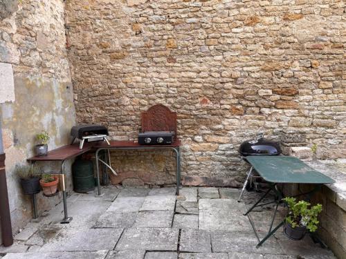 a brick wall with a grill and a table and chair at Maison intra muros in Langres