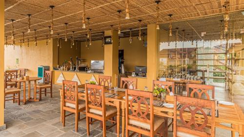 a restaurant with wooden tables and chairs and a bar at Munal and Mayur Resort - Wellness Retreat Pvt Ltd in Tikoli