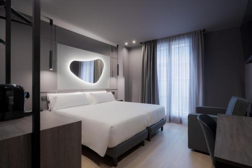a bedroom with a large white bed and a mirror at Hotel LIVVO La Escarlata in Las Palmas de Gran Canaria