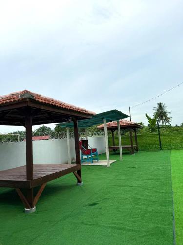 a group of picnic tables on a green lawn at Teratak EppyHoney'S in Kota Tinggi