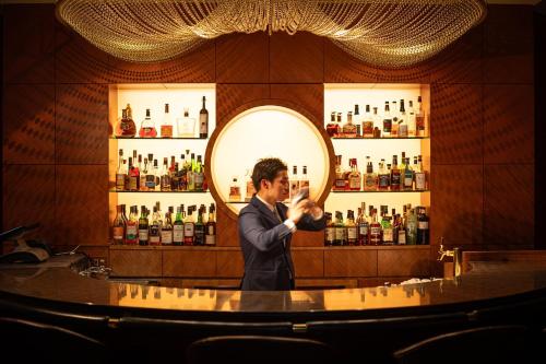 a man standing at a bar in front of a mirror at ANA Crowne Plaza Toyama by IHG in Toyama