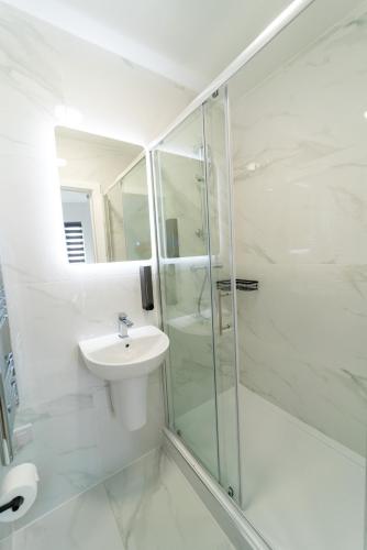 a white bathroom with a sink and a shower at Centra High Road in London