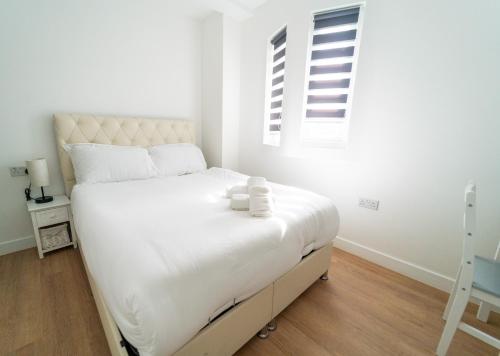 a bedroom with a large white bed with two candles on it at Centra High Road in London
