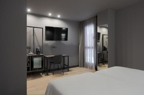 a bedroom with a bed and a desk with a television at Hotel LIVVO La Escarlata in Las Palmas de Gran Canaria