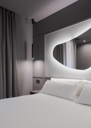a bedroom with a white bed and a mirror at Hotel LIVVO La Escarlata in Las Palmas de Gran Canaria