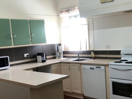 una cucina con armadi verdi ed elettrodomestici bianchi di KelBarsie - House - 1 Queen and 2 Singles a Maryborough