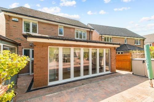 an extension to a brick house with sliding glass doors at Polmont Haven: Spacious 4- Bedroom Retreat in Polmont
