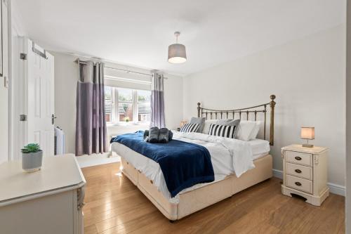 a white bedroom with a bed and a window at Polmont Haven: Spacious 4- Bedroom Retreat in Polmont