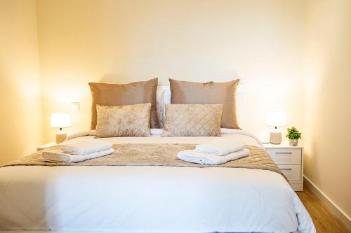a bedroom with a large white bed with two lamps at Hidden Corner by Sabugo House in Ponta do Sol