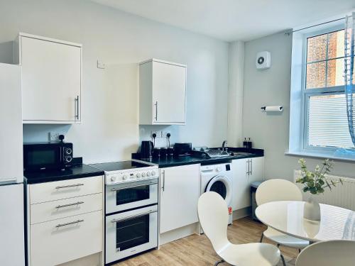 a kitchen with white appliances and a table with chairs at Rochester - Modern Flats Near Castle, Strood - Medway 1 or 2 Bedroom in Wainscot