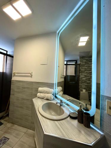 a bathroom with a sink with a large mirror at Moderno Depto Av América 2 habitaciones in Cochabamba