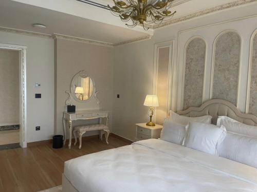 a bedroom with a large white bed and a desk at World Heart Residences in Baghdad