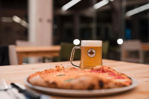 a pizza on a table with a mug of beer at Natural Village Resort in Porto Potenza Picena