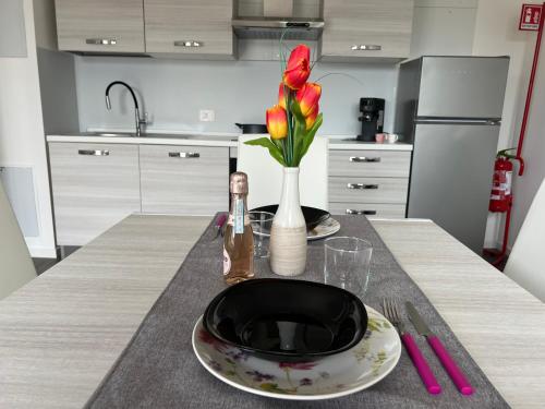 a table with a plate and a vase of flowers on it at Como Urban Loft - Parcheggio privato in Como