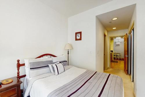 a bedroom with a bed with white sheets and a table at Olympic Pines Lodge in Olympic Valley
