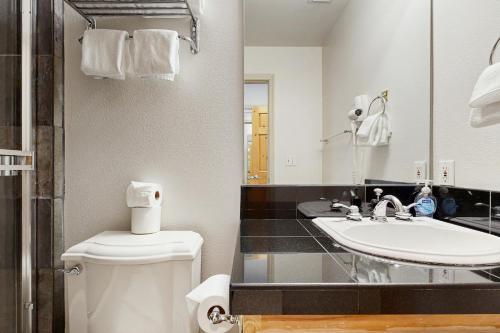 a bathroom with a sink and a toilet and a mirror at Olympic Pines Lodge in Olympic Valley