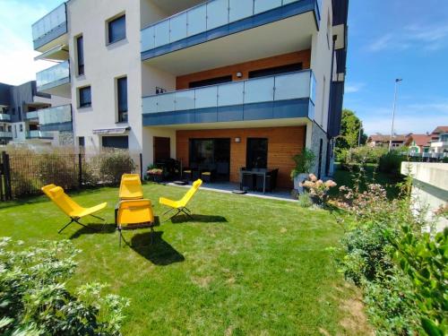 a yard with yellow chairs in front of a building at L'Escale du Léman in Publier
