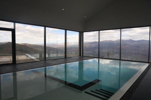 a swimming pool in a building with mountains in the background at Silken Mezio National Park in Soajo