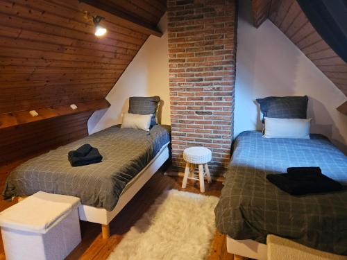 Un dormitorio con dos camas y una pared de ladrillo. en Gite Marie Le Bellanoy, en Wirwignes