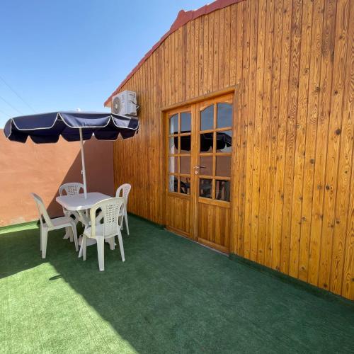 a patio with a table and chairs and an umbrella at Camping Riad Maissa in Dou Tourga