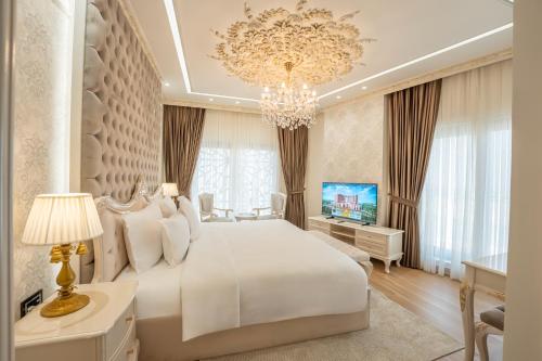 a bedroom with a large white bed and a chandelier at World Heart Residences in Baghdad