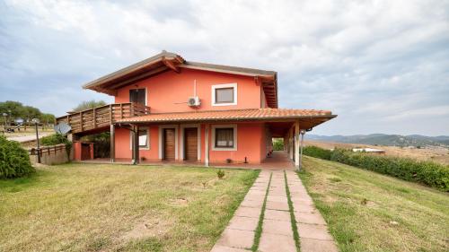 a small red house on a hill with a field at Tenuta dell'Argento Pool&Relax by Rentbeat in Civitavecchia