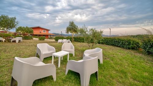 a group of white chairs sitting in the grass at Tenuta dell'Argento Pool&Relax by Rentbeat in Civitavecchia