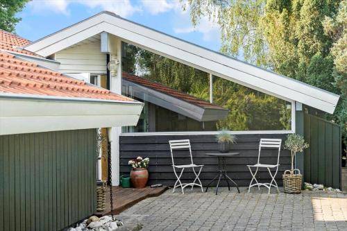 a patio with two chairs and a table in front of a house at 40106-Juelsminde-Fasanlunden-34 in Juelsminde