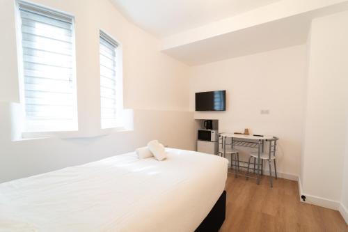 a white bedroom with a bed and a table at Centra High Road in London