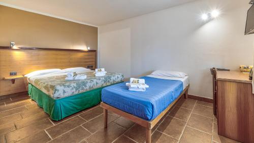a hotel room with two beds and a table at Tenuta dell'Argento Pool&Relax by Rentbeat in Civitavecchia